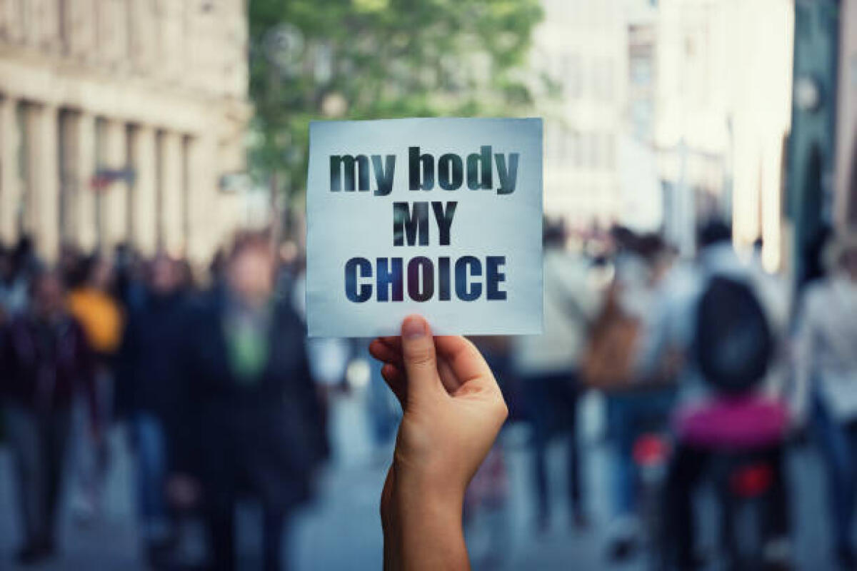 In quali paesi l'aborto non è legale? - Feminist hands holding a protest banner with the message my body my choice over a crowded street. Human rights concept against fetus law and reproductive justice. Stop discrimination and injustice.