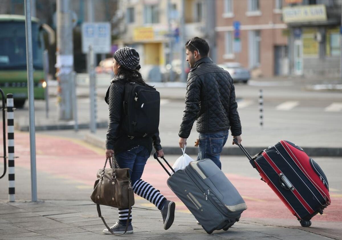 La valigia "senza spago" dei giovani che emigrano oggi - SOFIA, BULGARIA - DECEMBER 07:  A young Roma couple walk with suitcases outside the main bus station on December 7, 2013 in Sofia, Bulgaria. Restrictions on the freedom of Bulgarians and Romanians to work in the European Union are due to run out by D