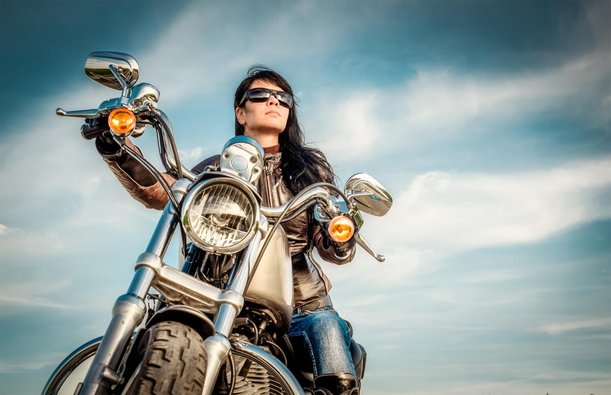 Le Donne e le Due Ruote: Superare gli Stereotipi nel Mondo delle Motociclette - Biker girl in a leather jacket on a motorcycle looking at the sunset.
