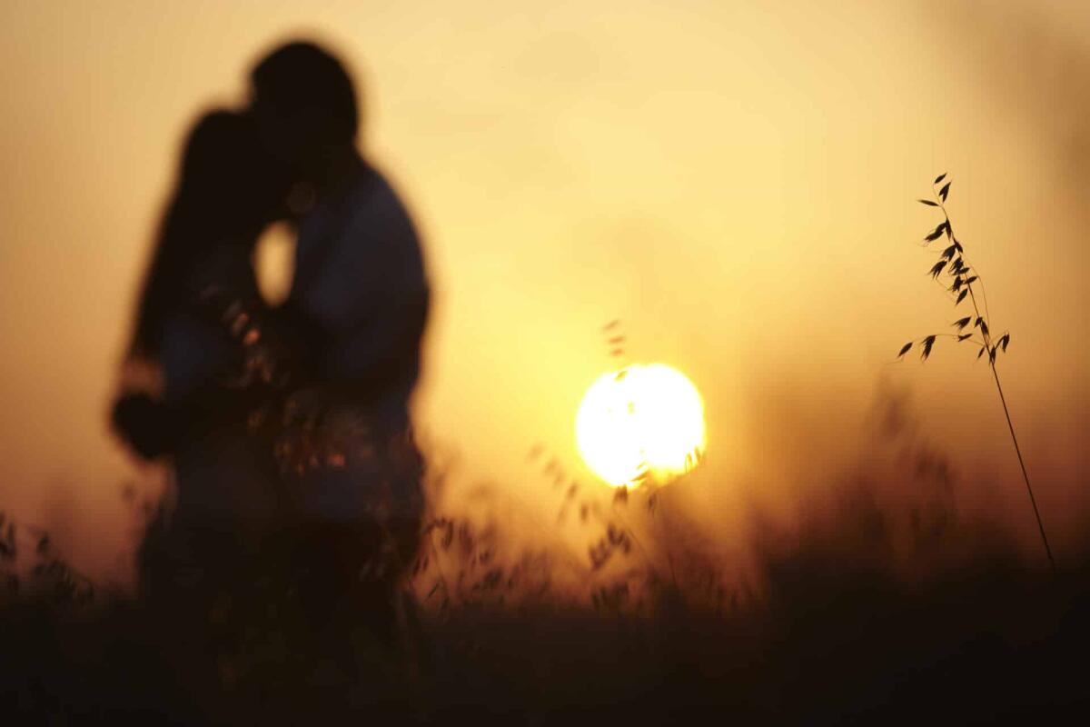 Relazione di coppia: gli elementi cardine per vivere un rapporto sereno - Pretty couple in the meadow on the sunset background